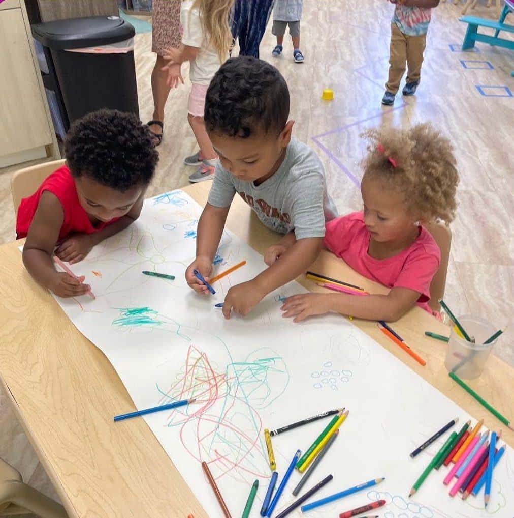 Preschoolers drawing together on a big sheet of paper