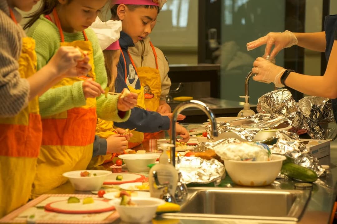 Students in chef hats and aprons cooking together