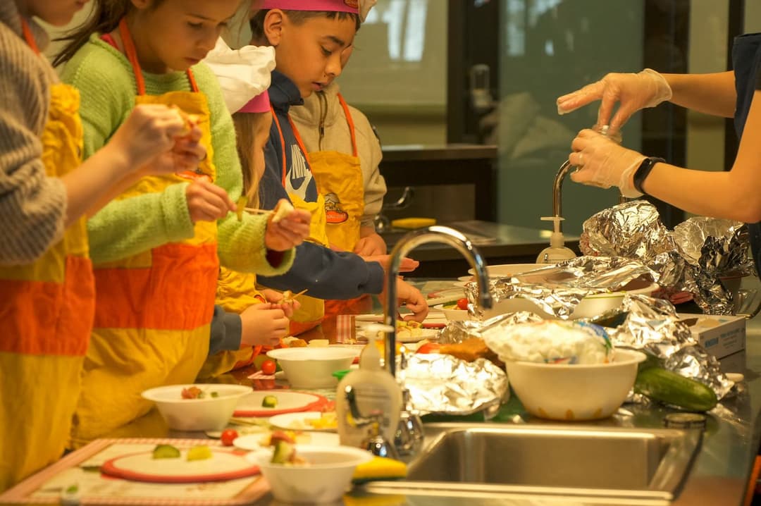 Students in chef hats cooking in the teaching kitchen