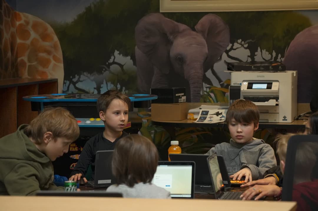 A student in a gray hoodie works on a laptop in the coding room