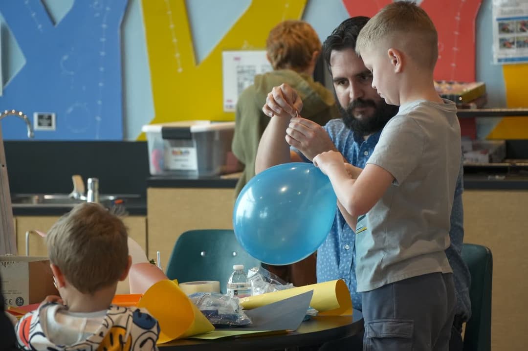 Children and a teacher doing a balloon science experiment