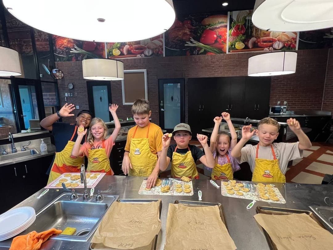 Kids in chef aprons cheering in the teaching kitchen